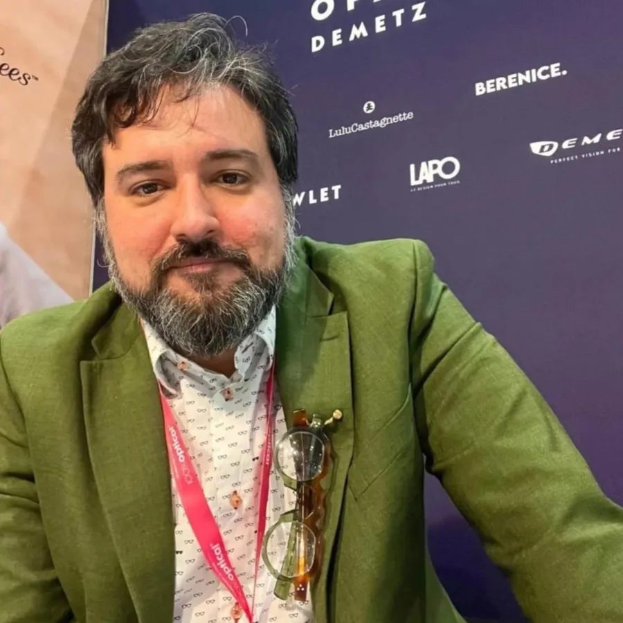 Man in a green blazer with glasses held by MagTag at an event