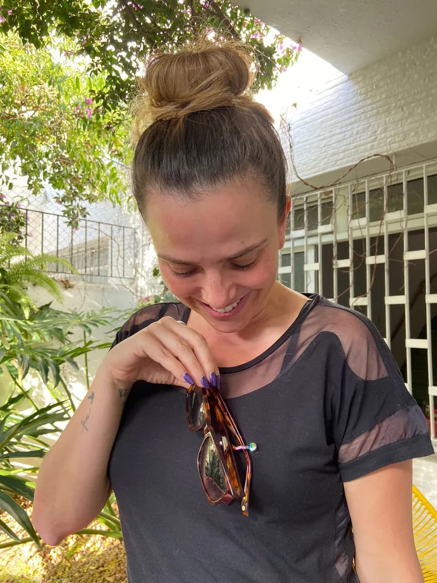 Smiling woman adjusting glasses held by MagTag